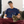 Load image into Gallery viewer, Person relaxing on a couch, wearing a navy ROCKaBLOCK CTA Cat Map graphic t-shirt featuring a cat silhouette made from Chicago transit lines, while petting a brown tabby cat sitting on their lap.
