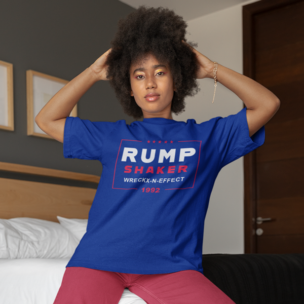A woman with hands in her natural hair wearing a blue ROCKaBLOCK graphic tee with the text 'RUMP SHAKER WRECKX-N-EFFECT 1992' printed on the front.