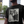 Load image into Gallery viewer, Man wearing a black graphic t-shirt featuring a vintage-style portrait of Martin Luther King Jr. alongside Clarence the Barber, set against a softly blurred urban street background.
