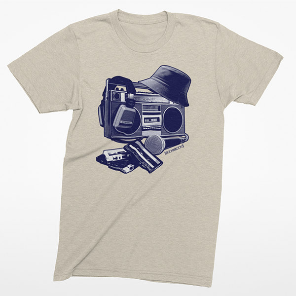 A light heather gray t-shirt with a dark blue graphic of a boombox, hat, and wallet on the front, displayed against a light gray background.
