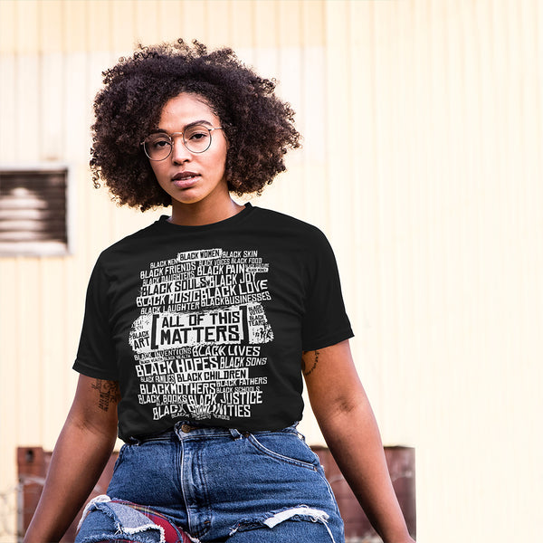 A woman with brown skin and natural hair wearing a black ROCKaBLOCK "All of This Matters" graphic tee.